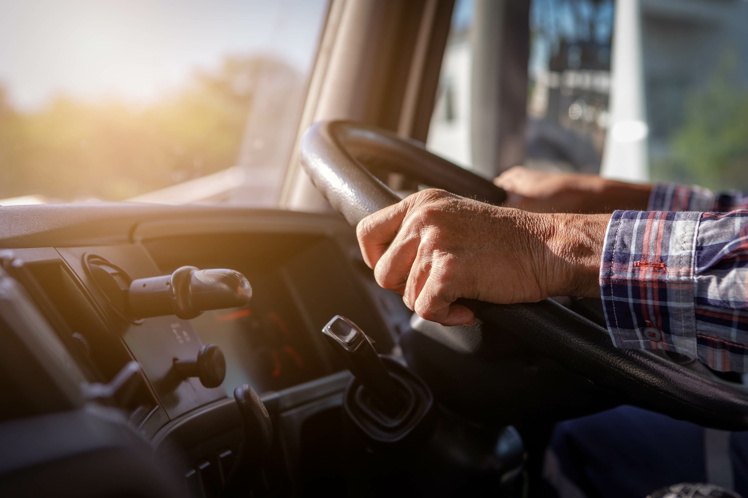 Truck driver keeps driving with one hands and change gears,The man Behind Semi Truck Steering Wheel,spot focus.