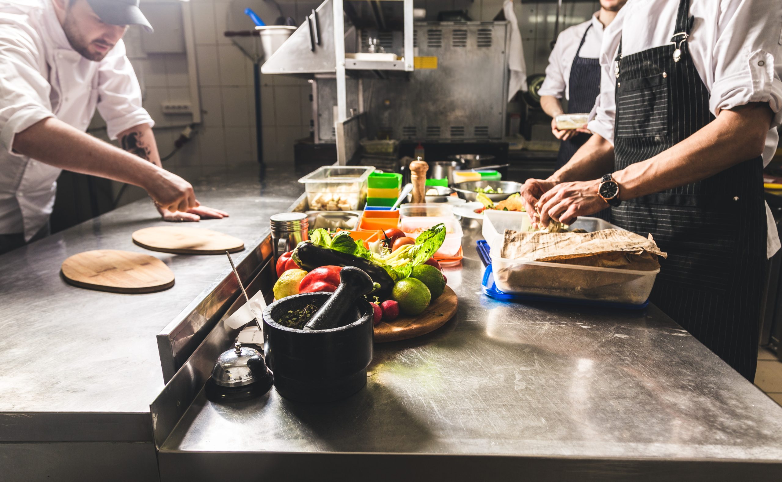 Professional chef cooking in the kitchen restaurant at the hotel, preparing dinner. A cook in an apron makes a salad of vegetables and pizza.