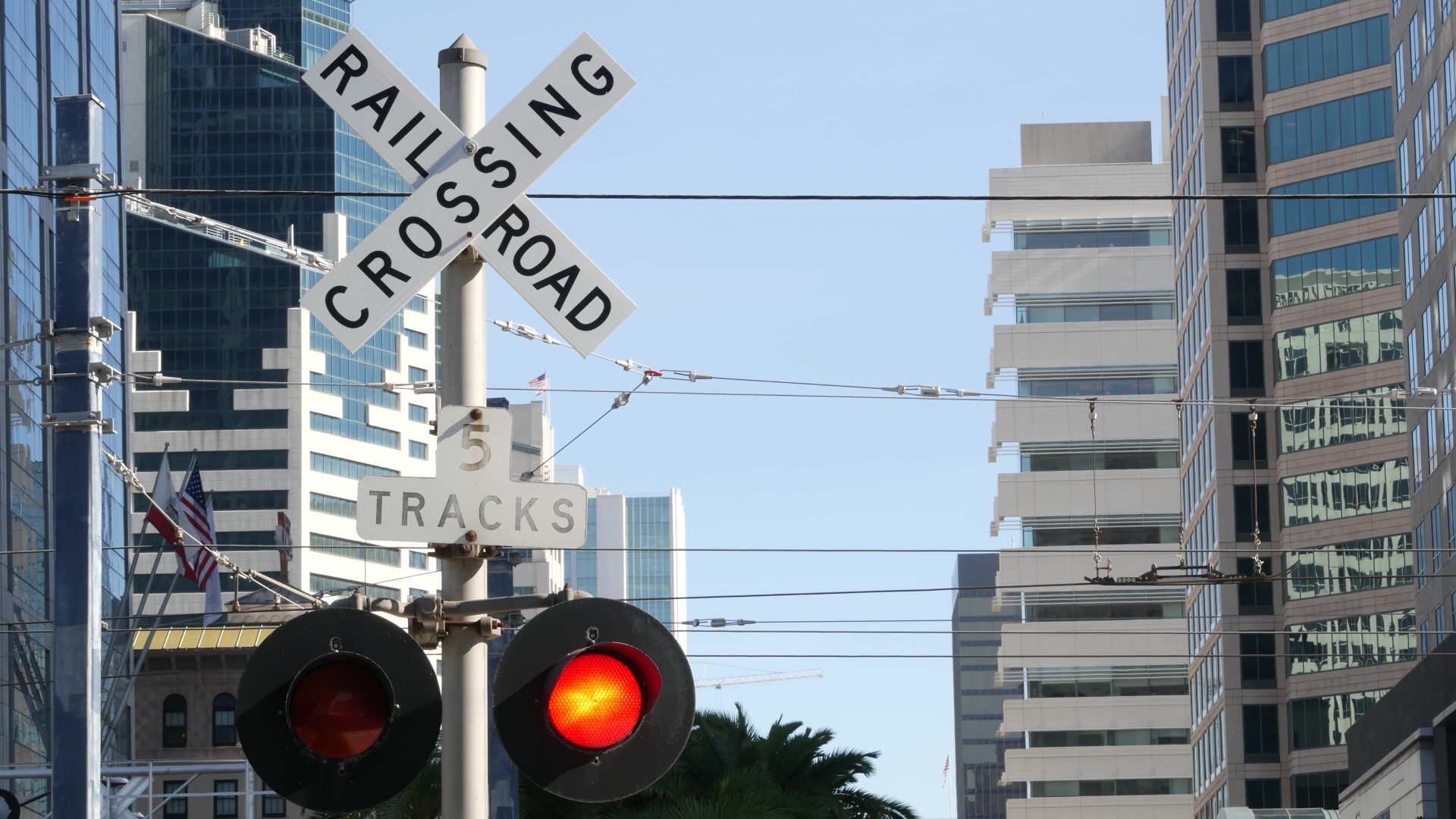 Level crossing warning signal in USA. Crossbuck notice and red traffic light on rail road intersection in California. Railway transportation safety symbol. Caution sign about hazard and train track