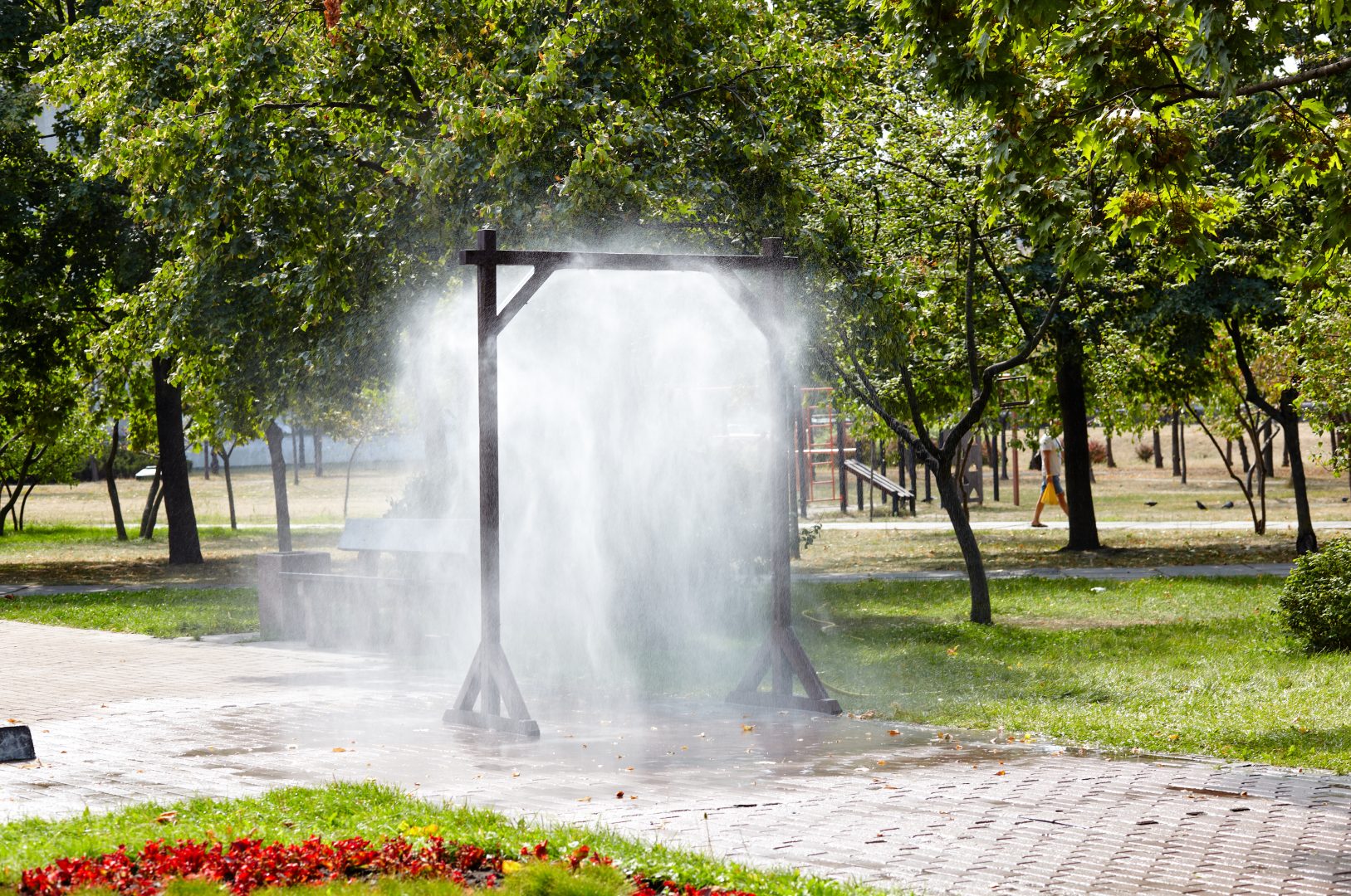 Water spray frame for cooling in hot weather on city street in Kyiv, Ukraine. Water mist cooling fog system in city park on hot summer. Protection against overheating and sunstroke by splashin