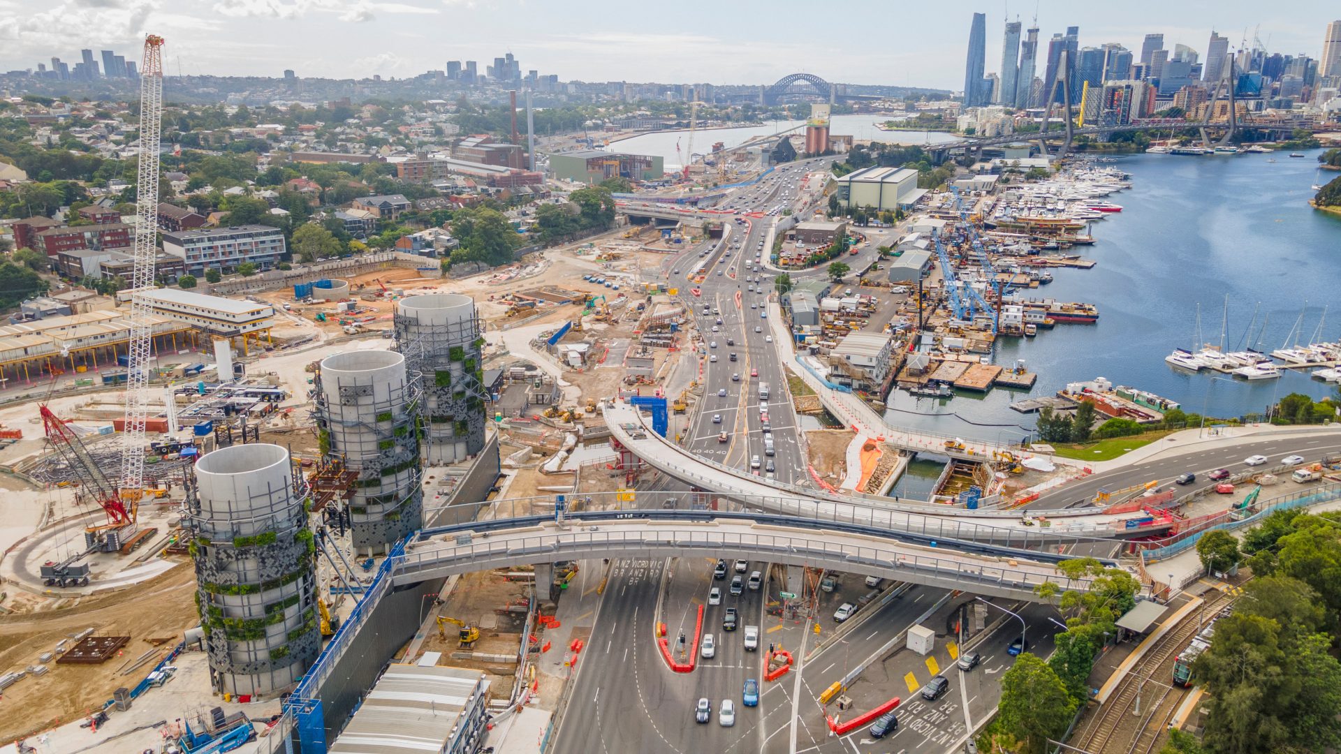 Aerial drone view of Rozelle Interchange showing major construction works and the large chimney towers with Anzac Bridge and Sydney City in the background in March 2023